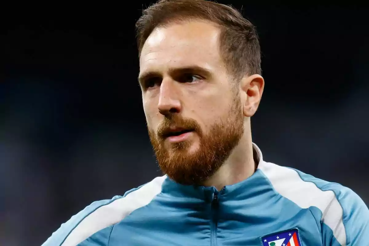 Un hombre con barba y chaqueta deportiva azul claro con el escudo de un equipo de fútbol.