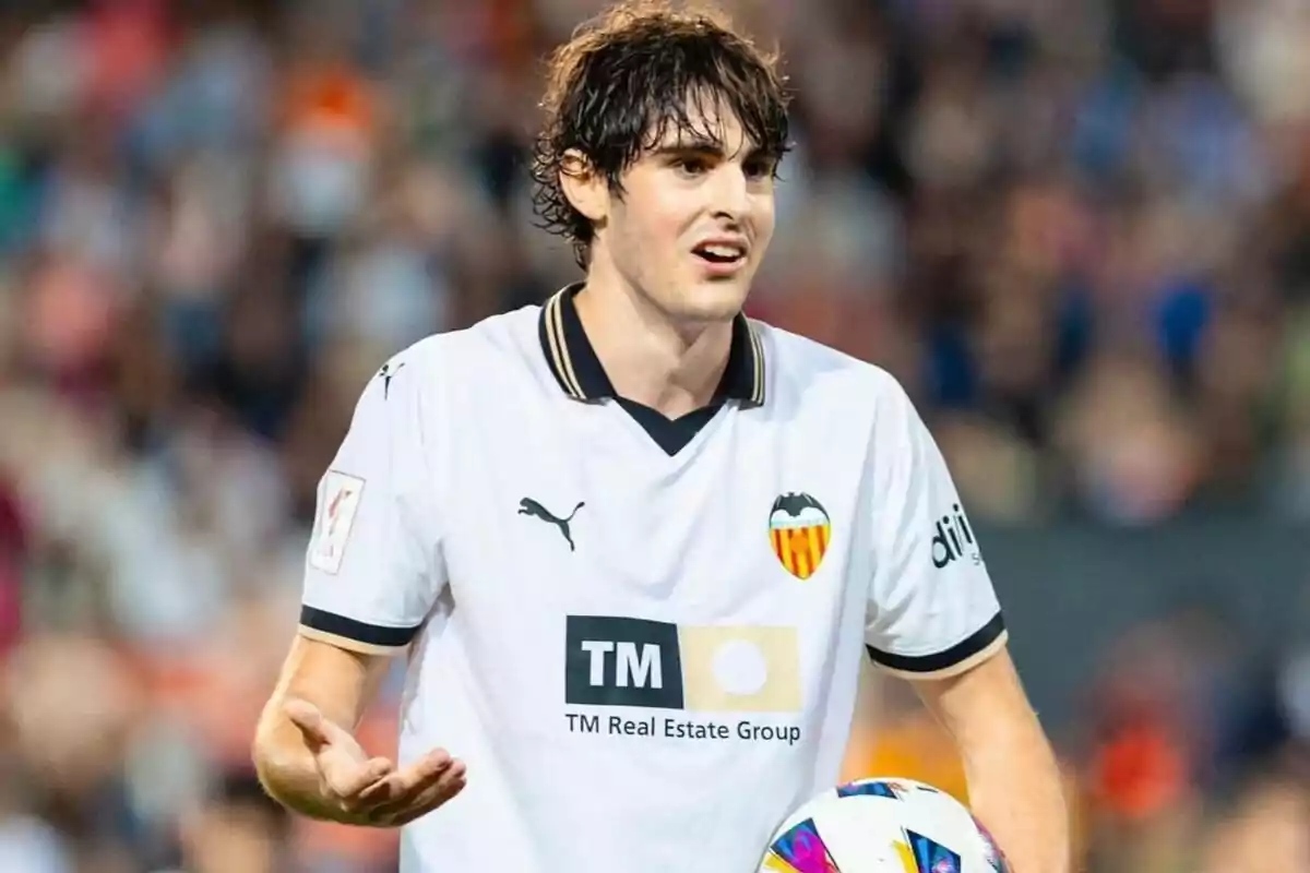 Jugador de fútbol con camiseta del Valencia CF en el campo.