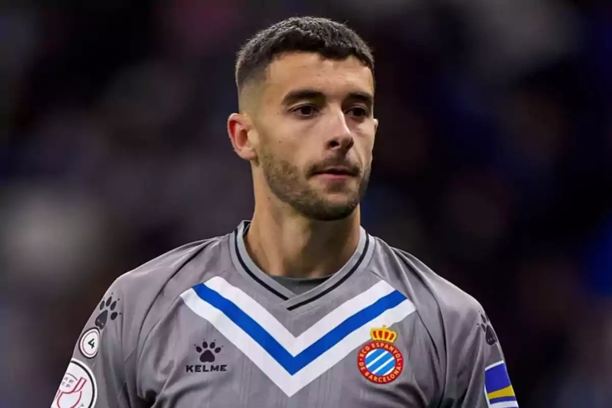 Jugador de fútbol con uniforme gris del RCD Espanyol de Barcelona en el campo de juego.