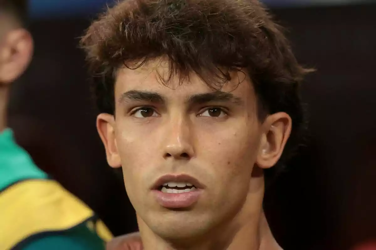 Un hombre joven con cabello oscuro y expresión seria, con un fondo desenfocado.