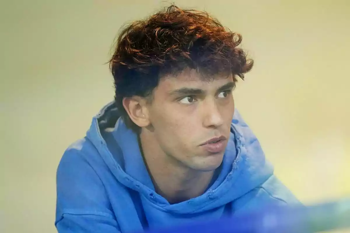 Un hombre joven con cabello rizado y una sudadera azul.