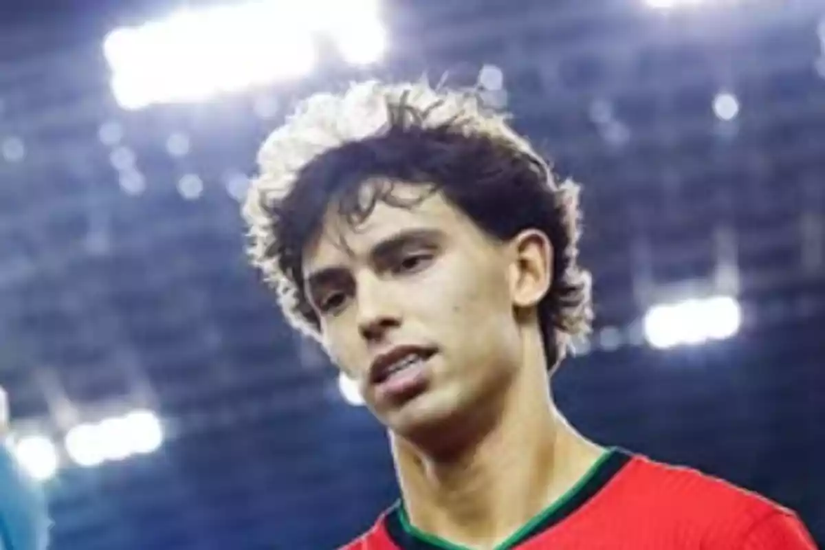 Un jugador de fútbol con camiseta roja en un estadio iluminado. Un jugador de fútbol con camiseta roja en un estadio iluminado.