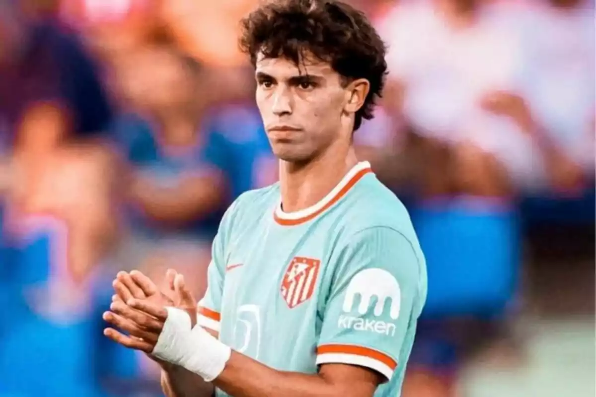 Un jugador de fútbol con uniforme verde claro aplaudiendo en un estadio.