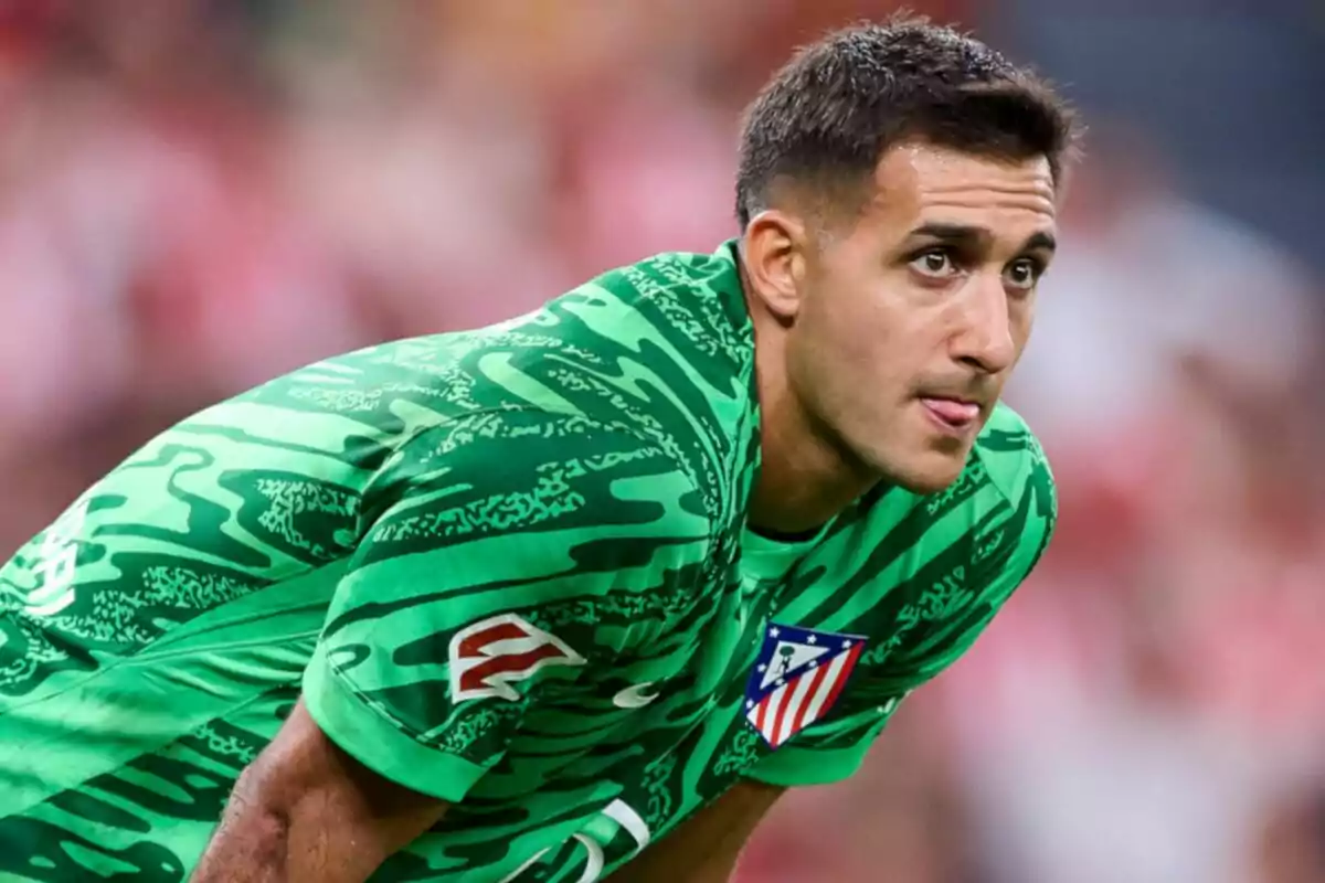 Jugador de fútbol con uniforme verde del Atlético de Madrid en el campo de juego.