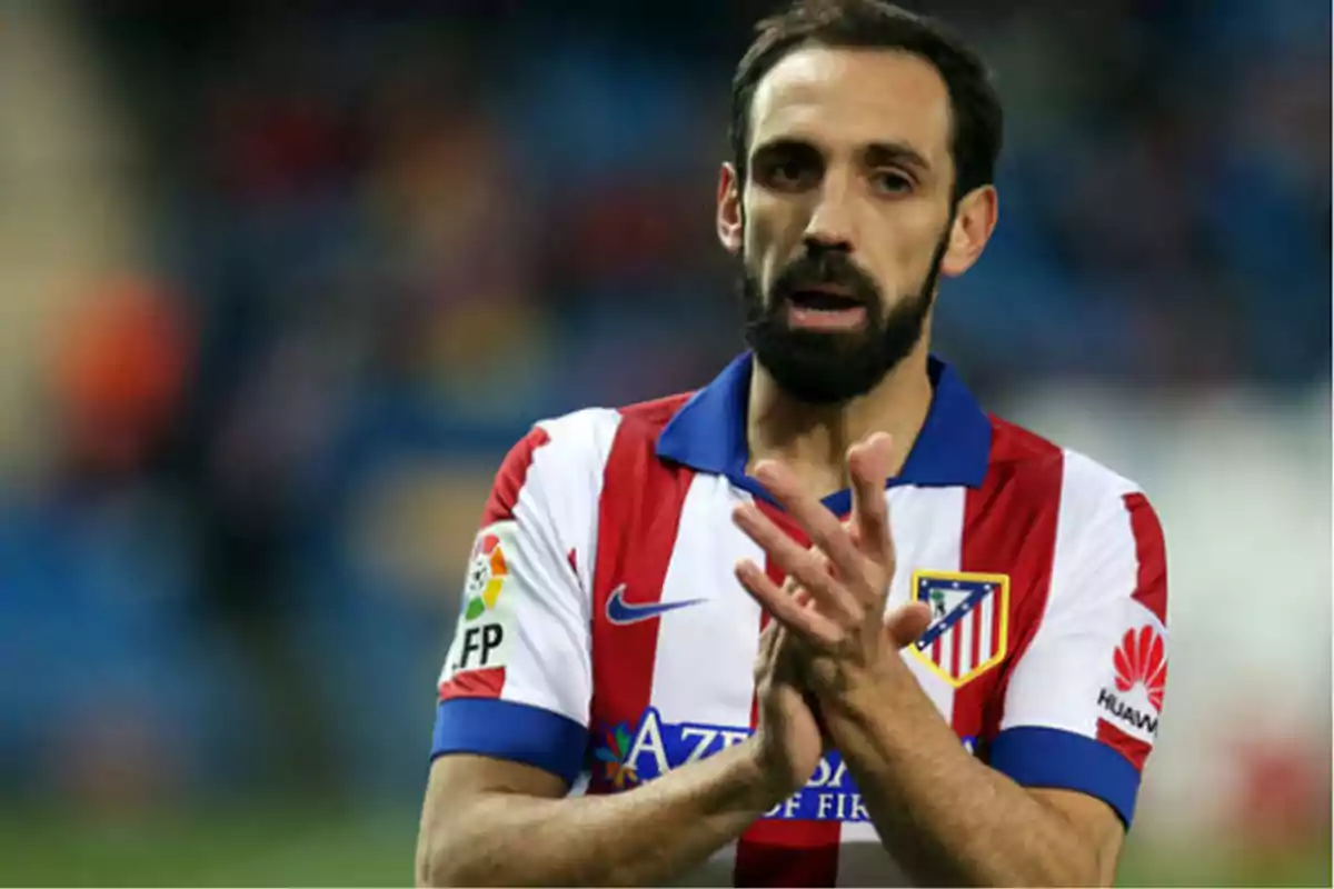 Jugador de fútbol con uniforme del Atlético de Madrid aplaudiendo en el campo. Jugador de fútbol con uniforme del Atlético de Madrid aplaudiendo en el campo.