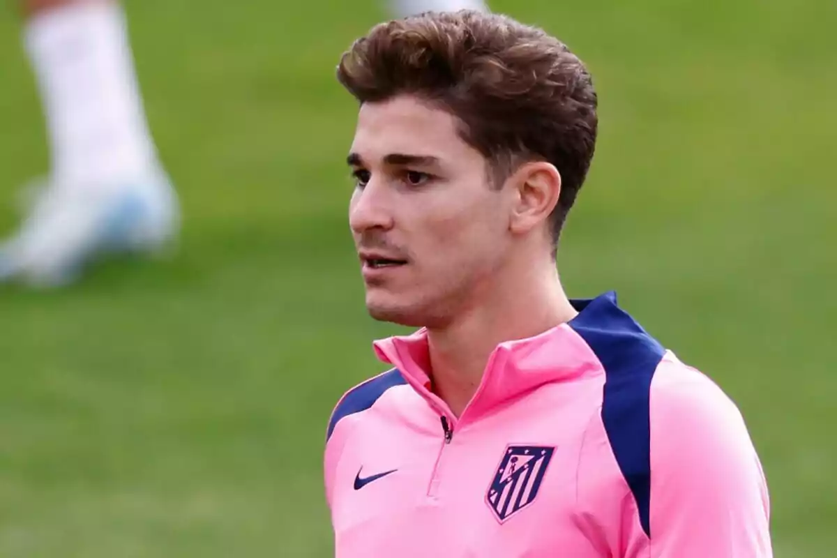 Un jugador de fútbol con uniforme rosa del Atlético de Madrid en un campo de entrenamiento.