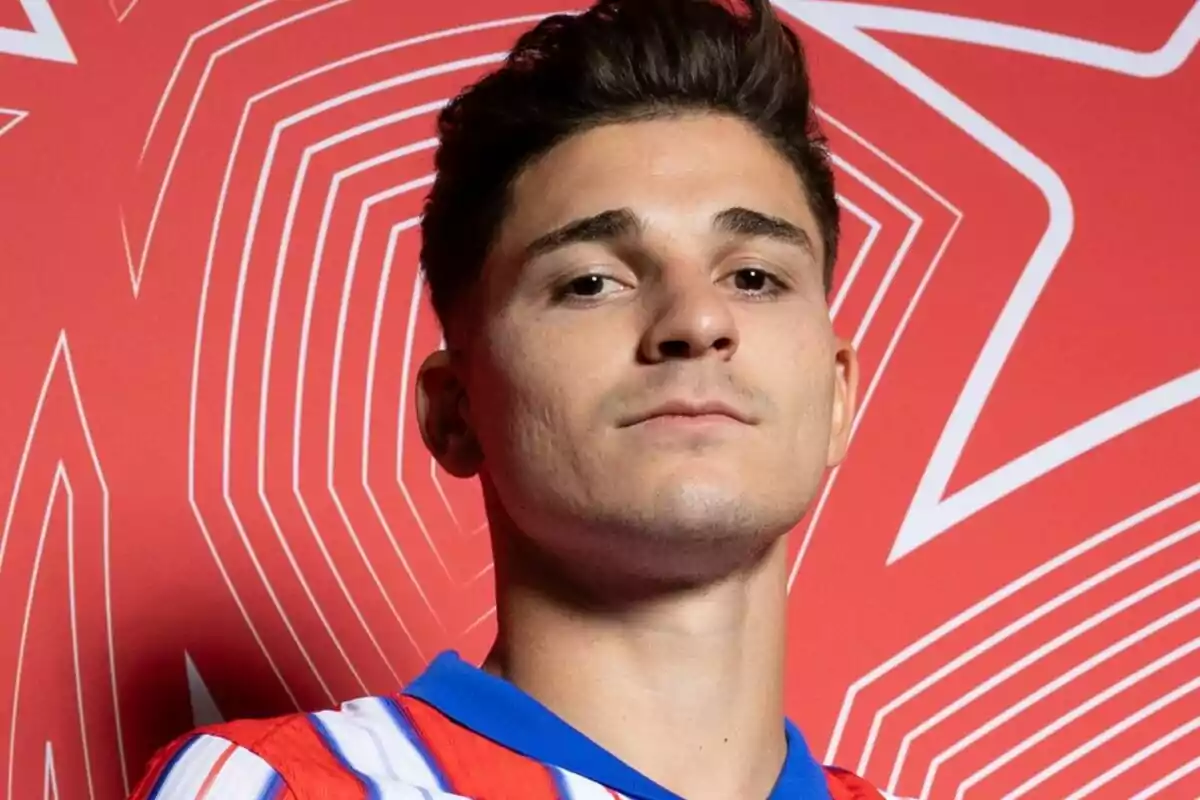 A man in a red and white striped t-jersey in front of a red background with geometric patterns.