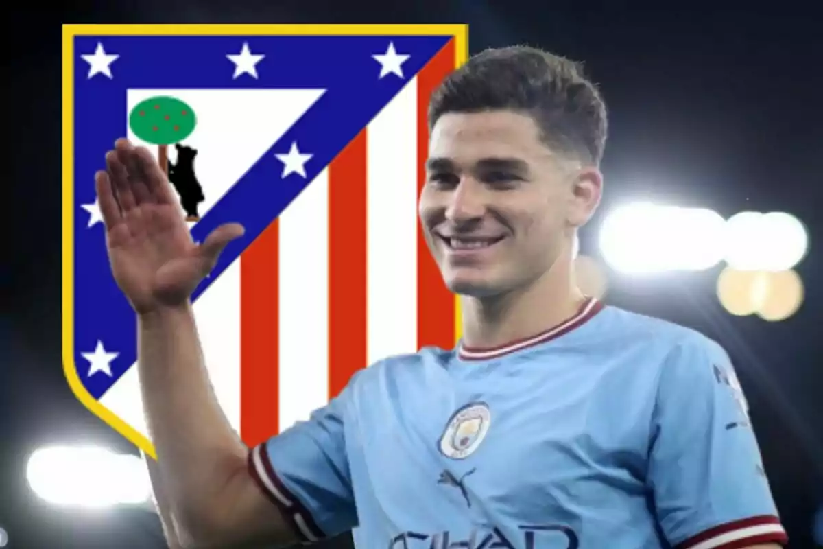 Un jugador de fútbol con la camiseta del Manchester City levantando la mano, con el escudo del Atlético de Madrid de fondo.