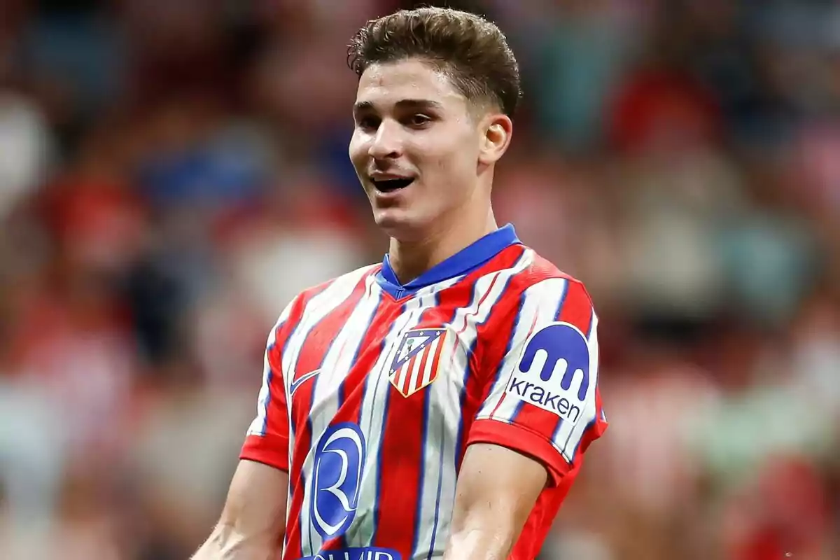 Jugador de fútbol con camiseta del Atlético de Madrid en el campo de juego.