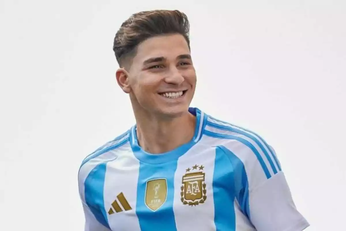 Un jugador de fútbol sonriente con la camiseta de la selección argentina.