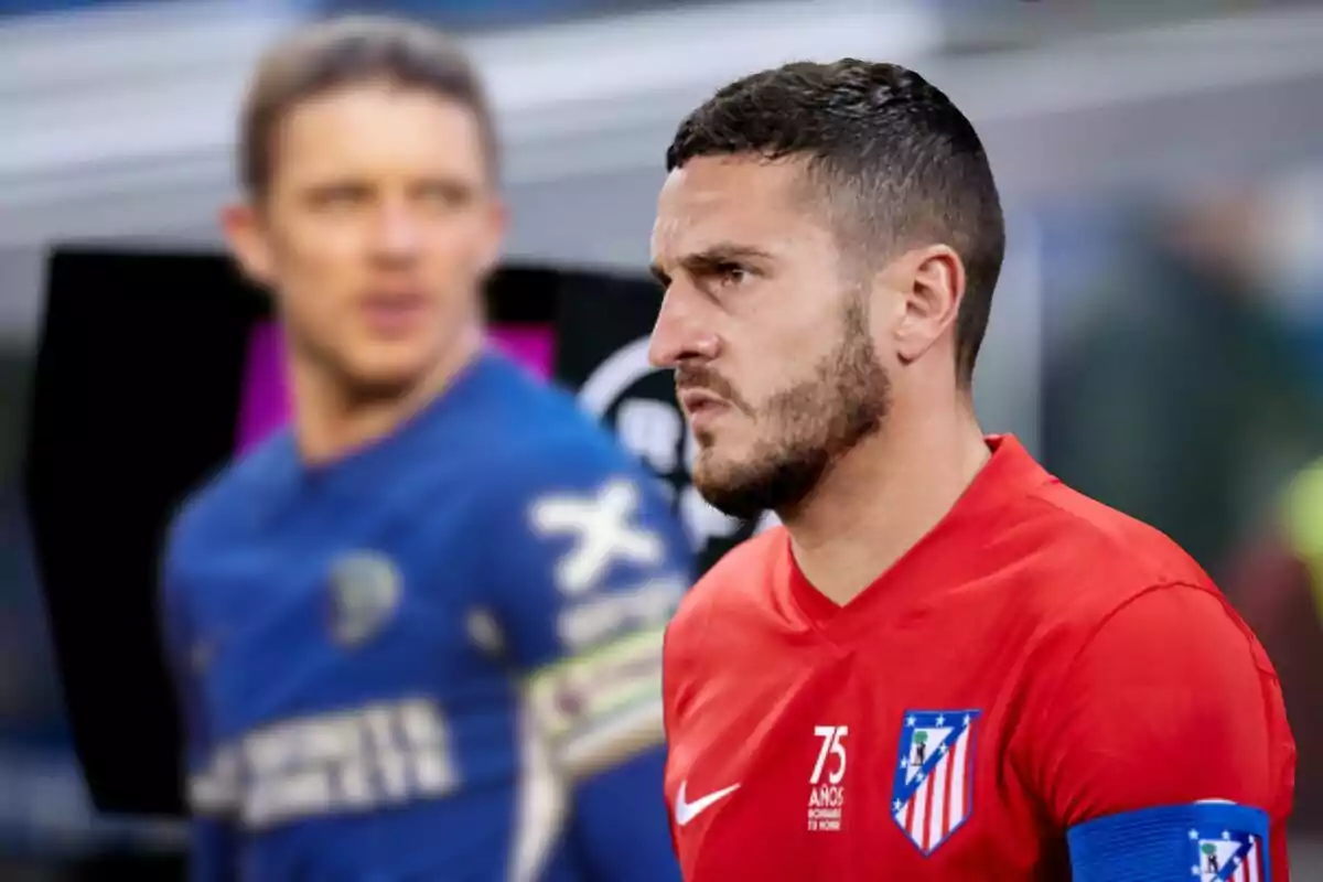 Dos jugadores de fútbol en el campo, uno con uniforme rojo del Atlético de Madrid y el otro con uniforme azul, ambos con brazaletes de capitán.