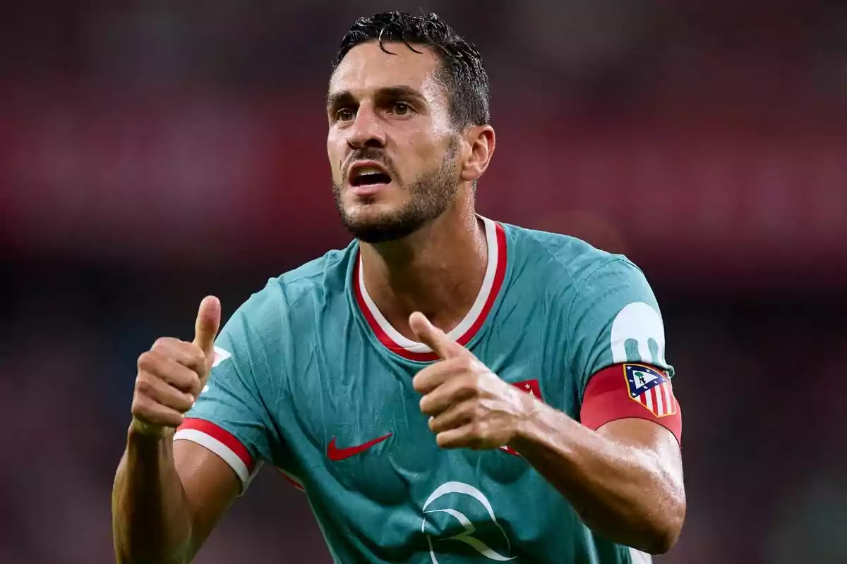 Jugador de fútbol con uniforme verde y brazalete de capitán levantando ambos pulgares.