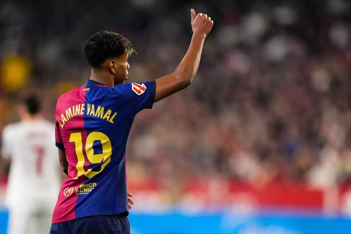 Un jugador de fútbol con el número 19 en su camiseta levanta el brazo en un estadio.