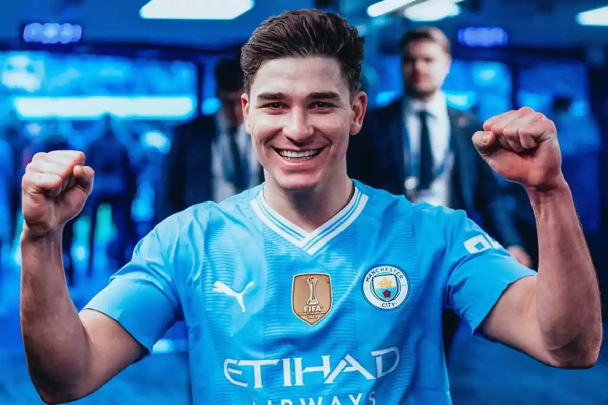 Un jugador de fútbol con la camiseta del Manchester City celebrando con los puños en alto y sonriendo.