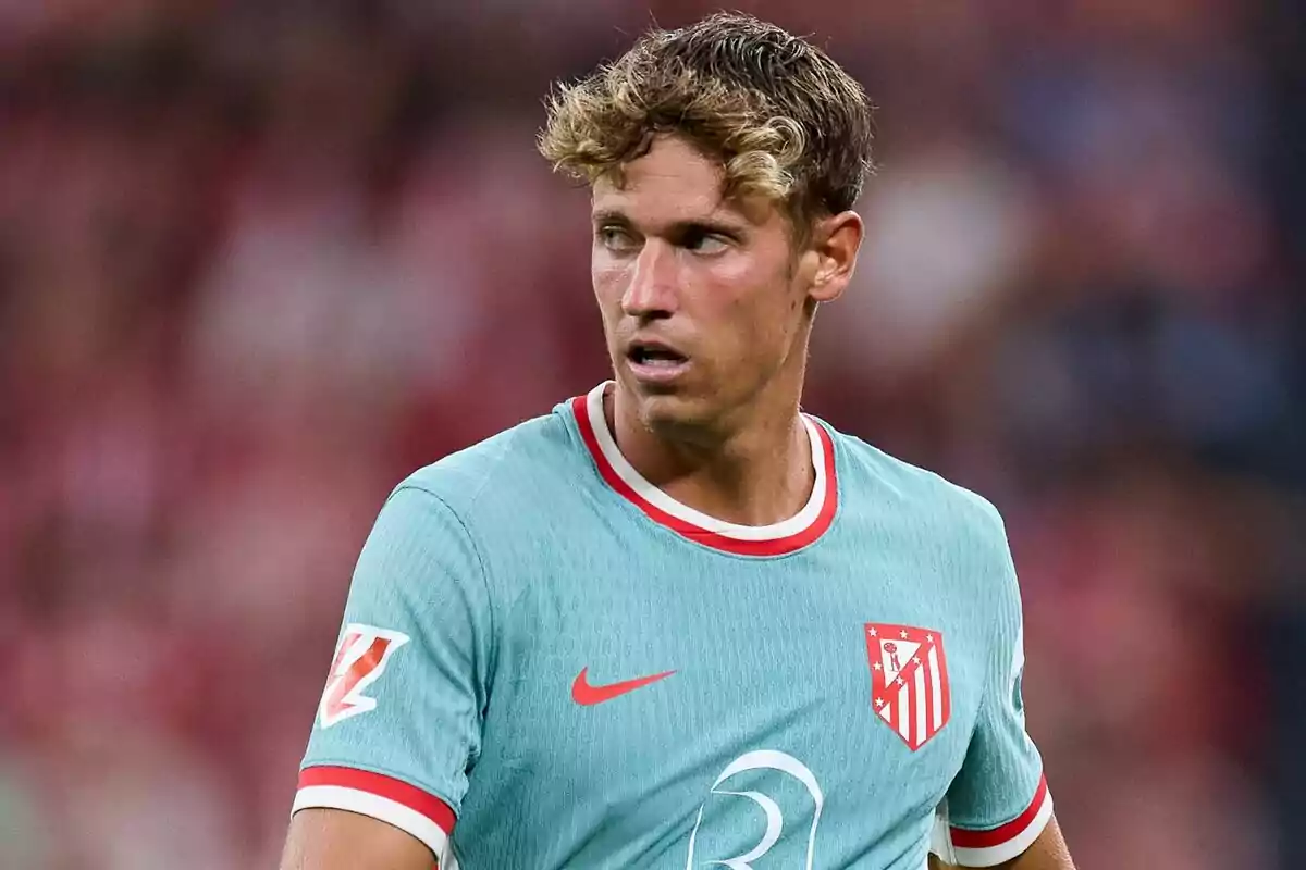 Jugador de fútbol con camiseta celeste del Atlético de Madrid en el campo de juego.