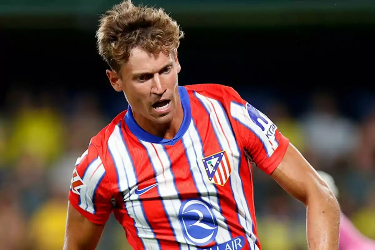 Jugador de fútbol con camiseta del Atlético de Madrid en acción durante un partido.