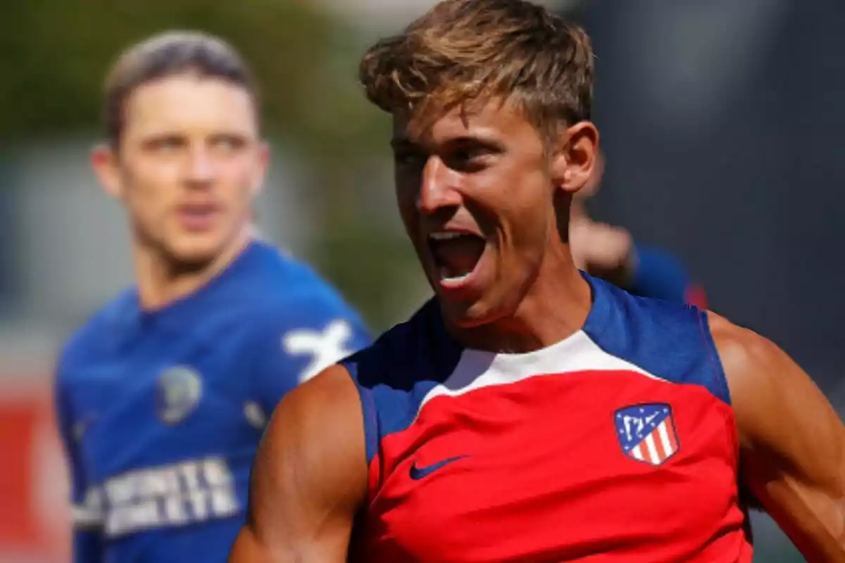 Dos jugadores de fútbol en el campo, uno con una camiseta roja del Atlético de Madrid y el otro con una camiseta azul, ambos en medio de una acción intensa.