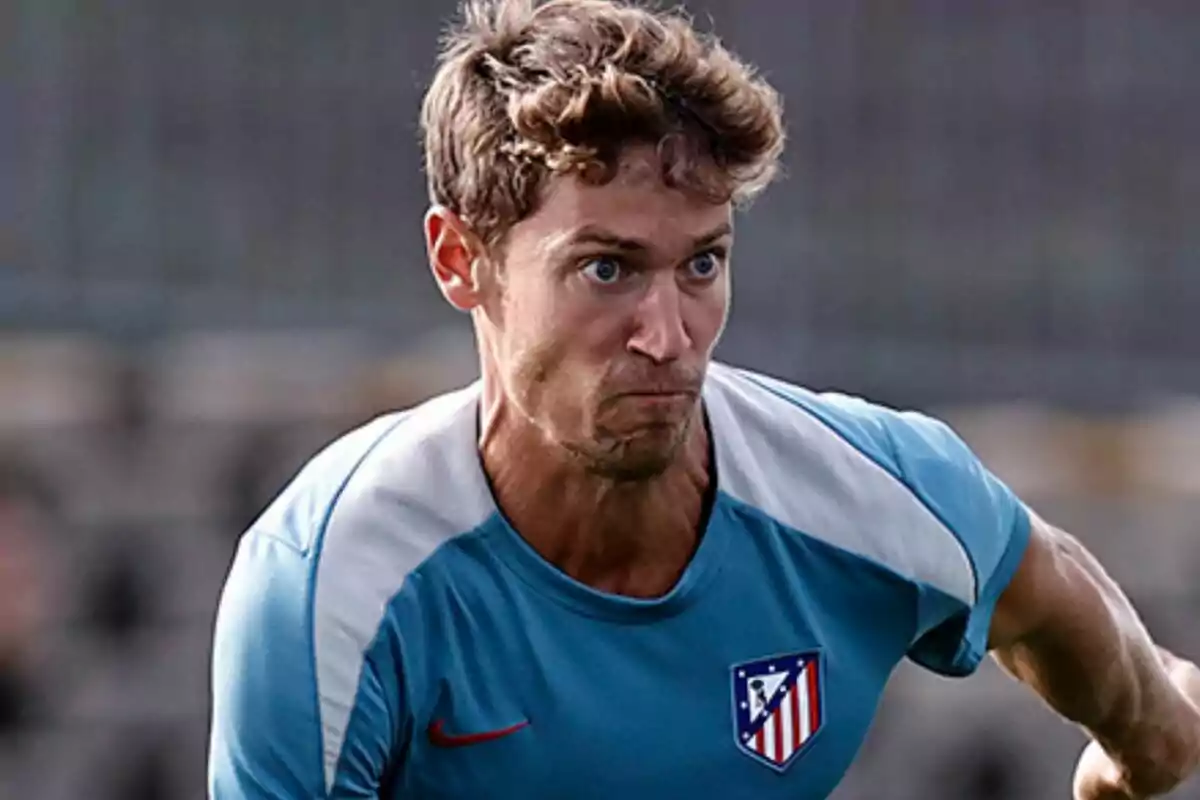 Un jugador de fútbol con camiseta azul del Atlético de Madrid en acción durante un partido.