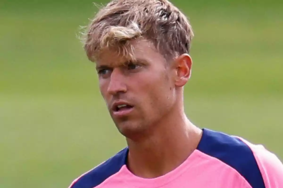 A man in a pink and blue t-jersey on a green field.