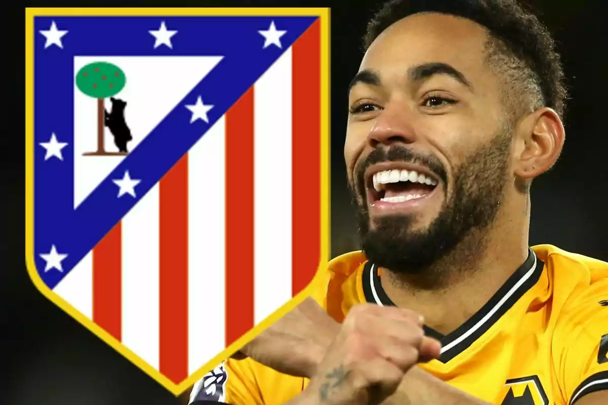 Un jugador de fútbol sonríe mientras lleva una camiseta amarilla, junto al escudo del Atlético de Madrid.