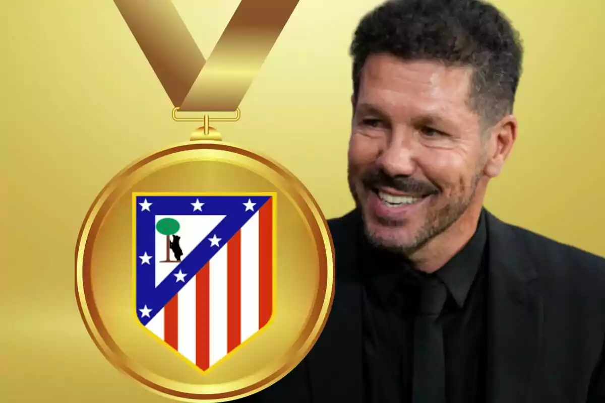 Hombre sonriendo junto a una medalla con el escudo del Atlético de Madrid sobre un fondo dorado.