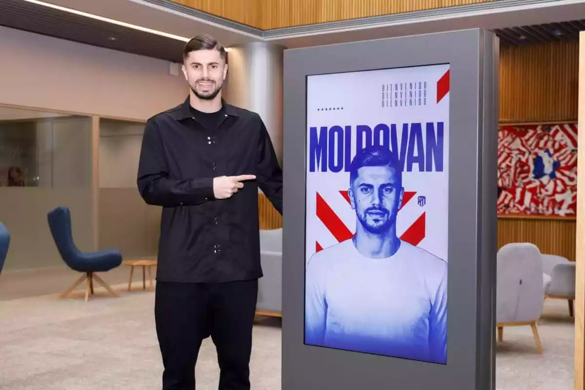 Moldovan posando junto a una imagen de su fichaje por el Atlético de Madrid
