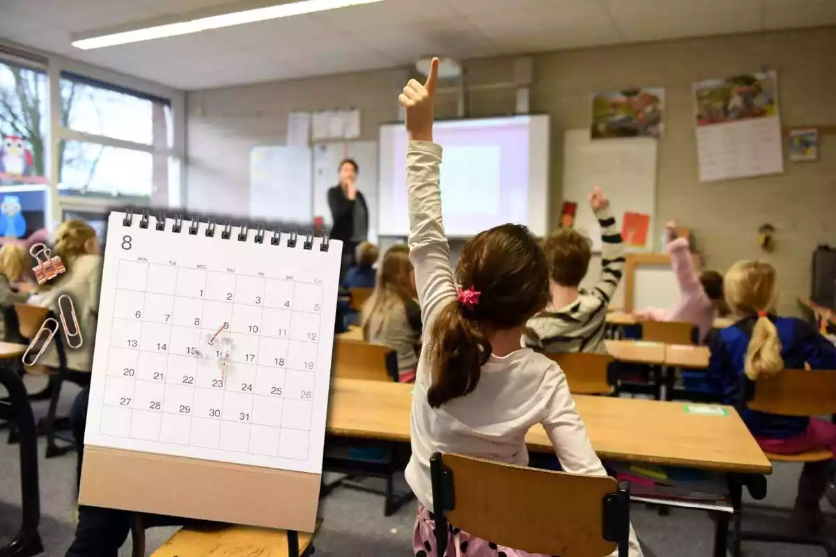 Montaje con el interior de una clase con niños levantando el brazo y un calendario Montaje con el interior de una clase con niños levantando el brazo y un calendario