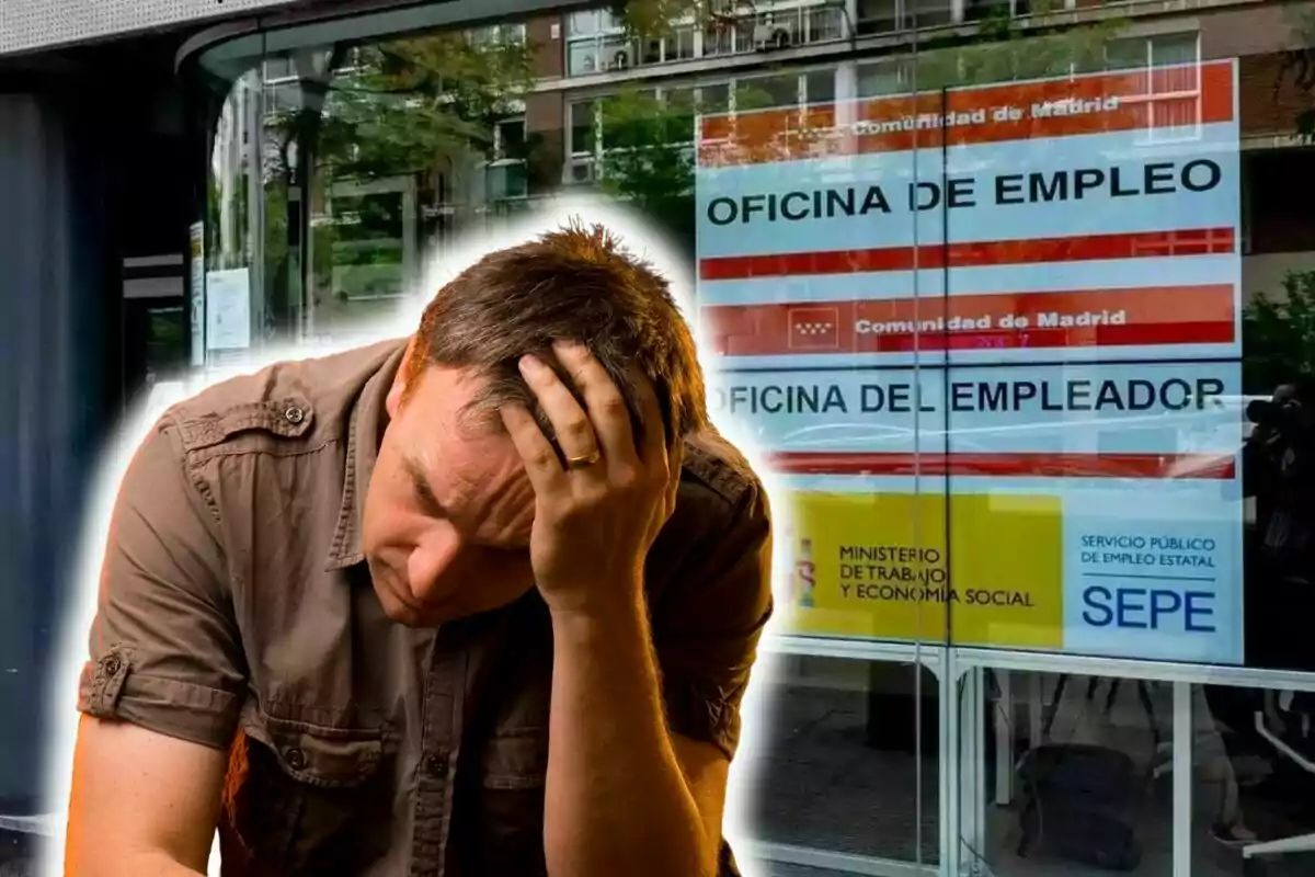 Un hombre con expresión de preocupación se sostiene la cabeza con la mano frente a una oficina de empleo en Madrid.