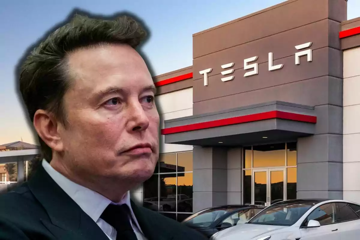 Un hombre con traje oscuro frente a un edificio de Tesla con autos estacionados.