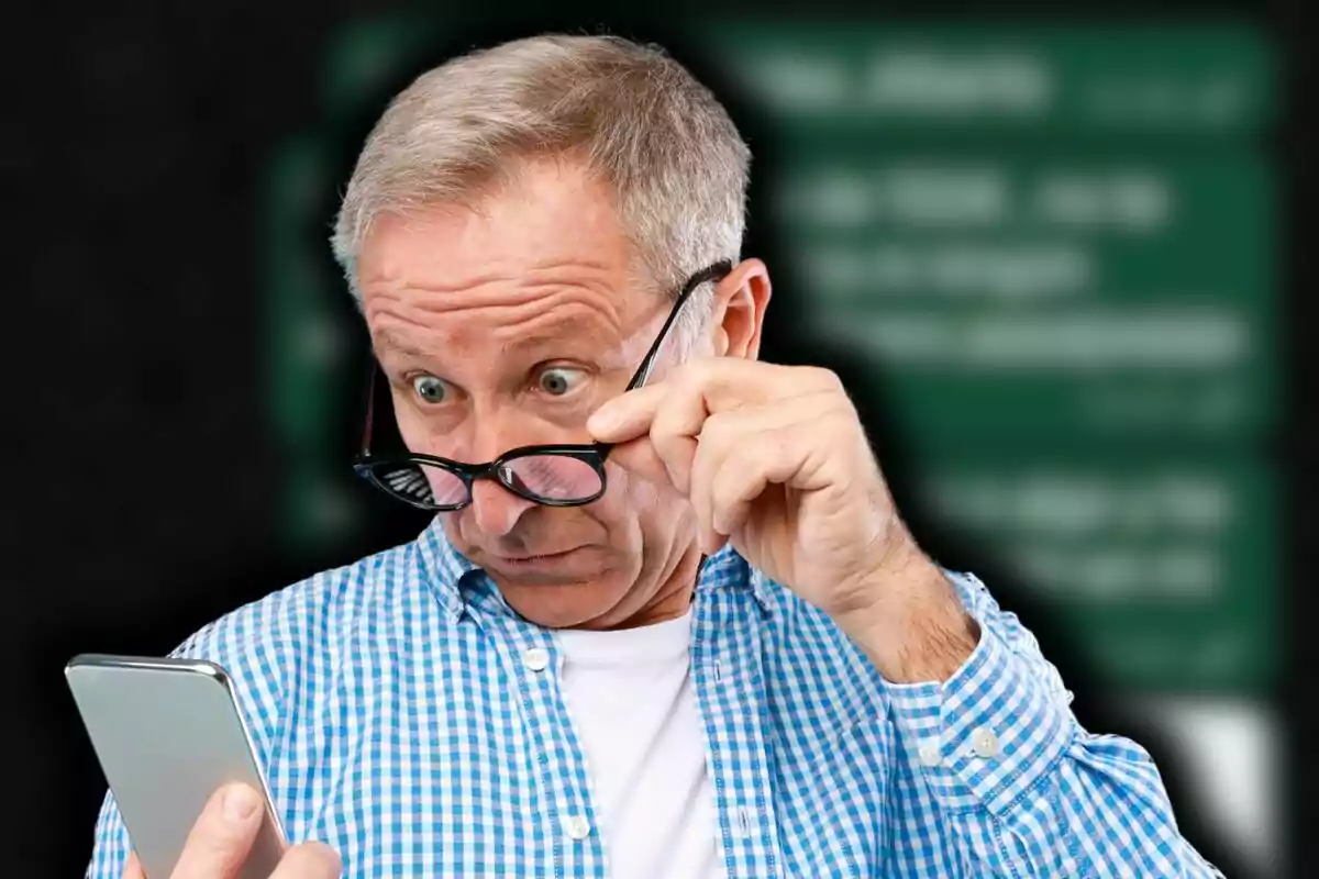 Hombre mayor con camisa a cuadros azules mirando sorprendido su teléfono mientras se ajusta las gafas. Hombre mayor con camisa a cuadros azules mirando sorprendido su teléfono mientras se ajusta las gafas.