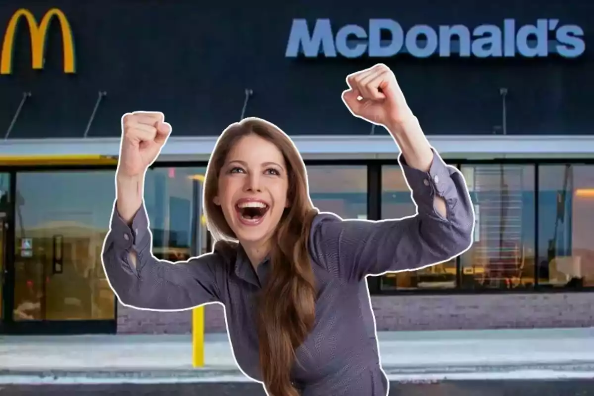 Mujer joven sonriente levantando los brazos con entusiasmo frente a un restaurante de McDonald's Mujer joven sonriente levantando los brazos con entusiasmo frente a un restaurante de McDonald's