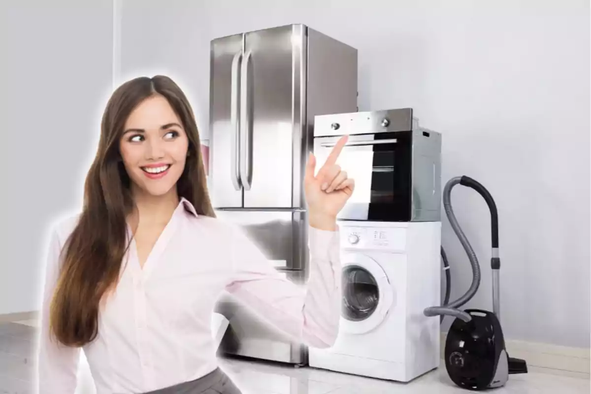 A smiling woman points to a set of appliances that includes a refrigerator, washing machine, oven and vacuum cleaner. A smiling woman points to a set of appliances that includes a refrigerator, washing machine, oven and vacuum cleaner.