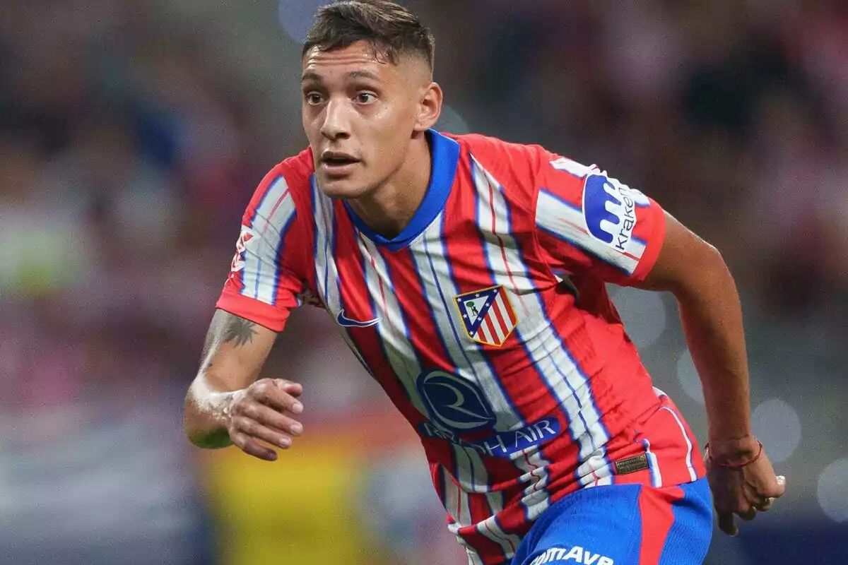 Jugador de fútbol con uniforme del Atlético de Madrid en acción durante un partido.