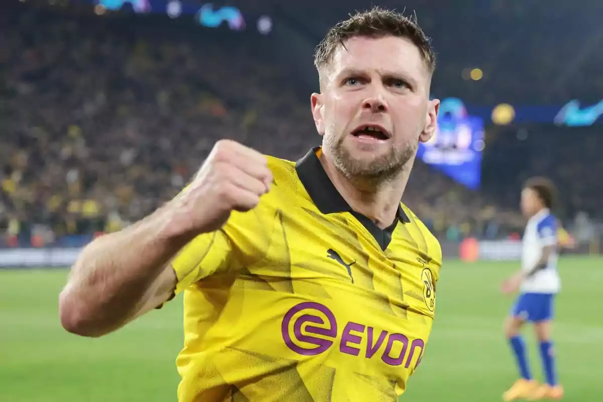 Jugador de fútbol celebrando un gol con la camiseta del Borussia Dortmund en un estadio lleno de espectadores.