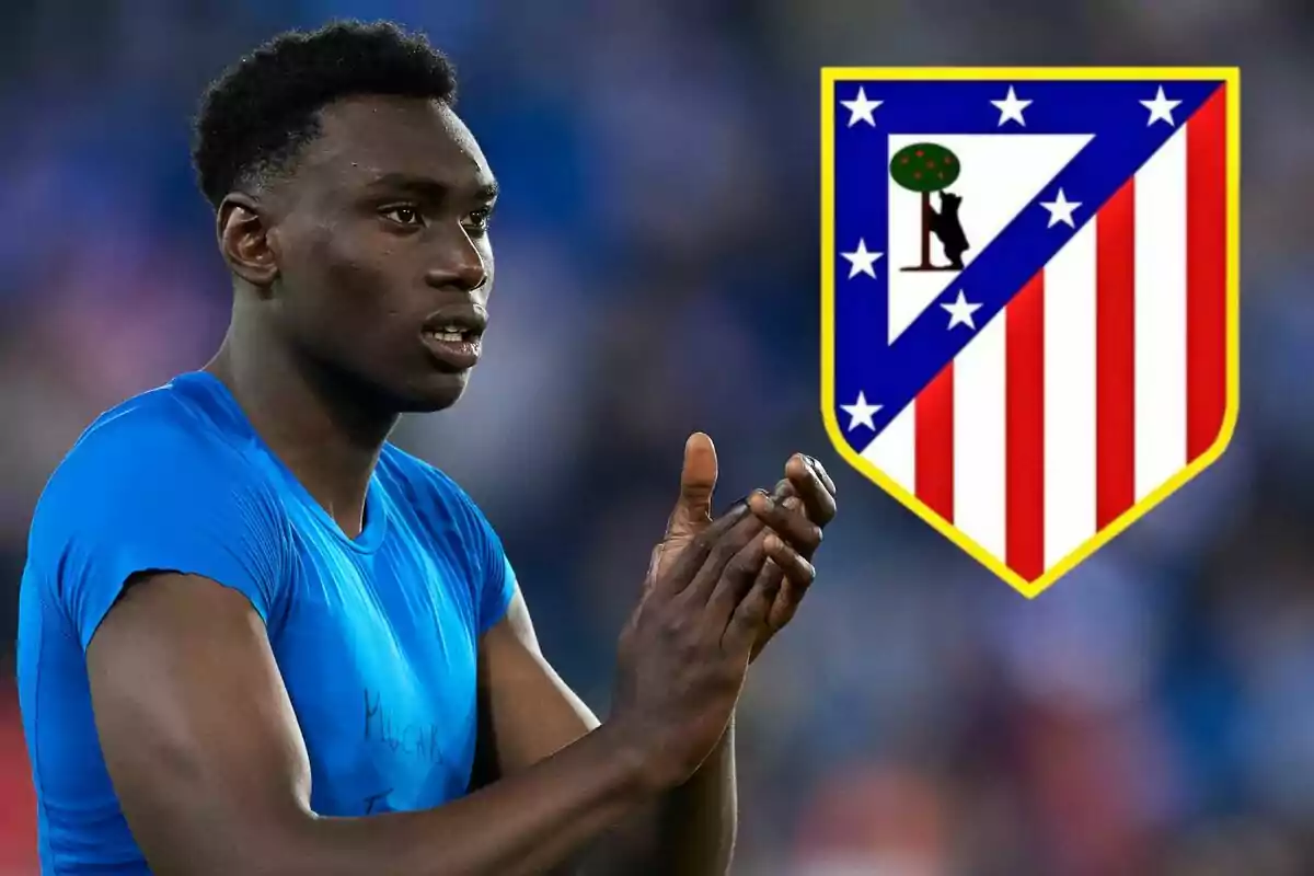 Un jugador de fútbol aplaudiendo con el escudo del Atlético de Madrid al fondo.