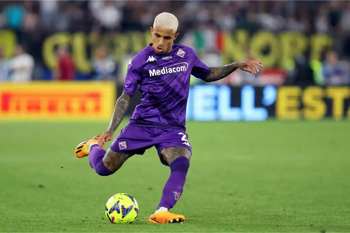 Jugador de fútbol con uniforme morado pateando un balón en el campo durante un partido. Jugador de fútbol con uniforme morado pateando un balón en el campo durante un partido.