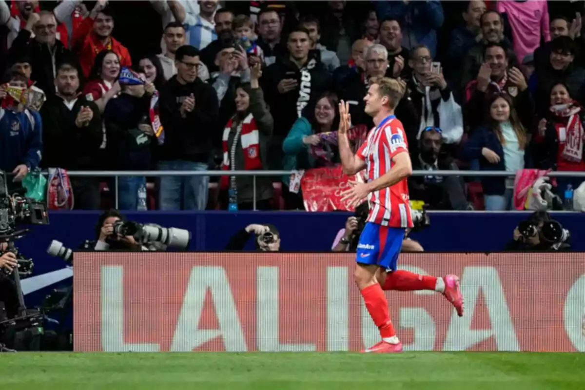 Un jugador de fútbol celebra frente a una multitud de aficionados en un estadio, mientras fotógrafos capturan el momento. Un jugador de fútbol celebra frente a una multitud de aficionados en un estadio, mientras fotógrafos capturan el momento.