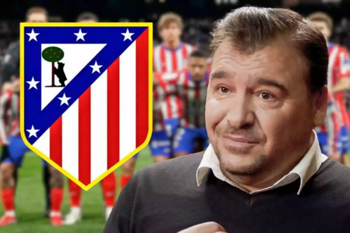 Un hombre con suéter oscuro y camisa blanca aparece frente al escudo de un equipo de fútbol con fondo de jugadores desenfocados.
