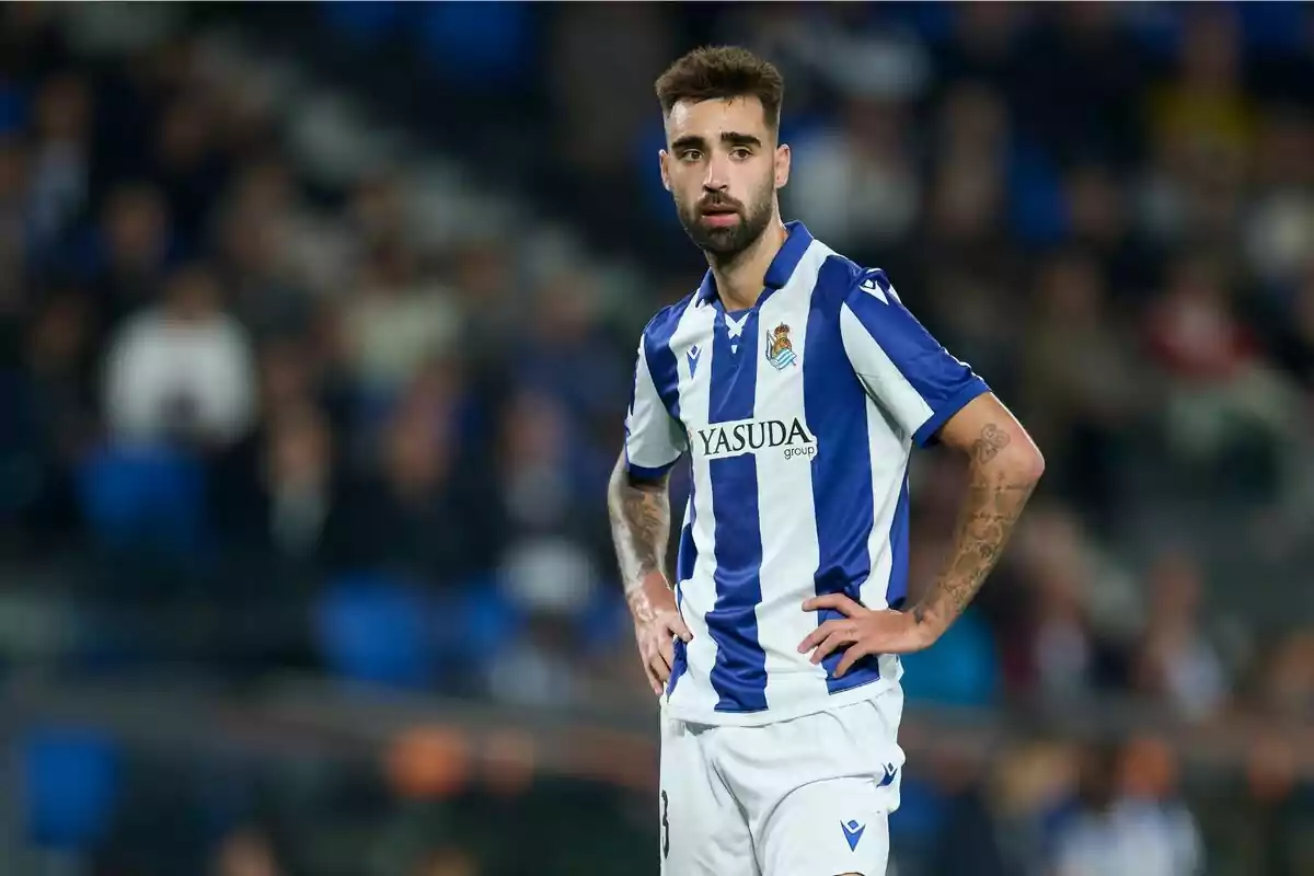 Un jugador de fútbol con uniforme azul y blanco de pie en el campo durante un partido. Un jugador de fútbol con uniforme azul y blanco de pie en el campo durante un partido.