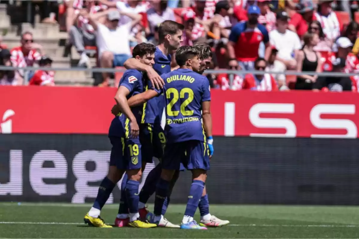 Jugadores de fútbol con uniforme azul celebran en el campo mientras el público observa desde las gradas. Jugadores de fútbol con uniforme azul celebran en el campo mientras el público observa desde las gradas.