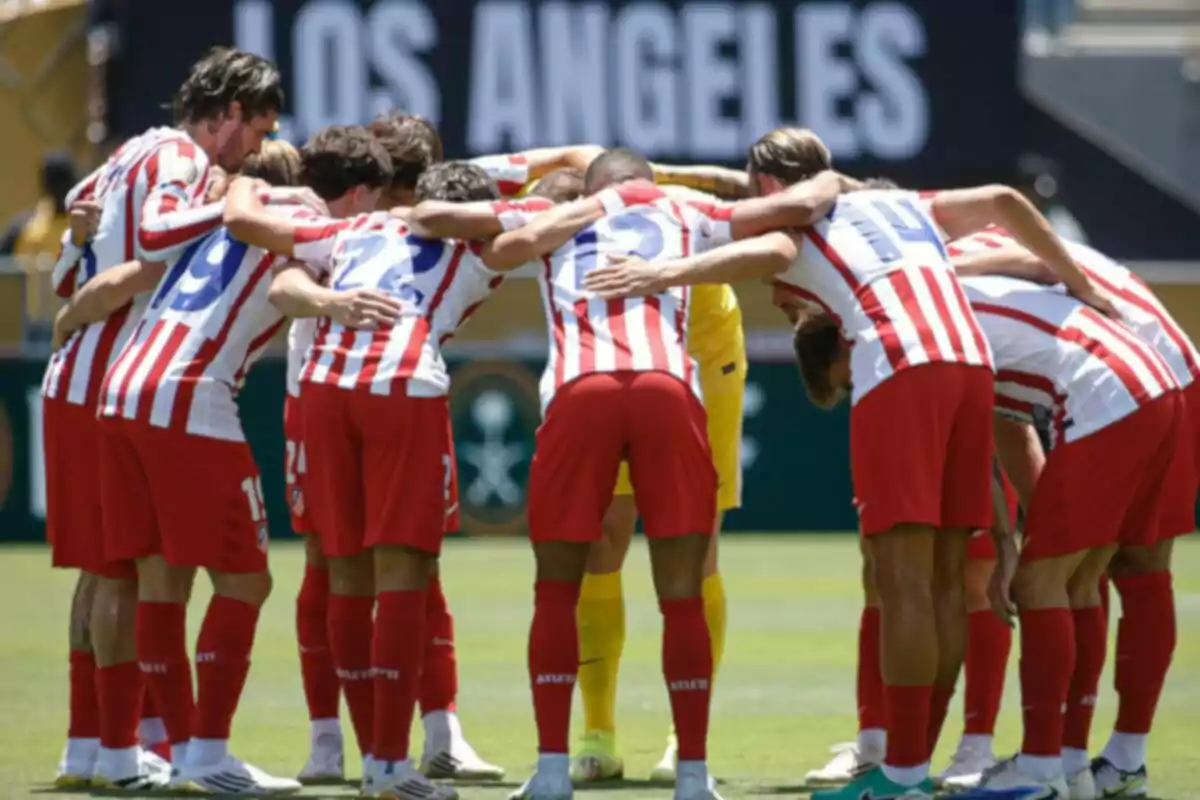 Jugadores de fútbol con uniforme de rayas rojas y blancas y pantalones rojos reunidos en círculo abrazados antes de un partido en un estadio al aire libre Jugadores de fútbol con uniforme de rayas rojas y blancas y pantalones rojos reunidos en círculo abrazados antes de un partido en un estadio al aire libre