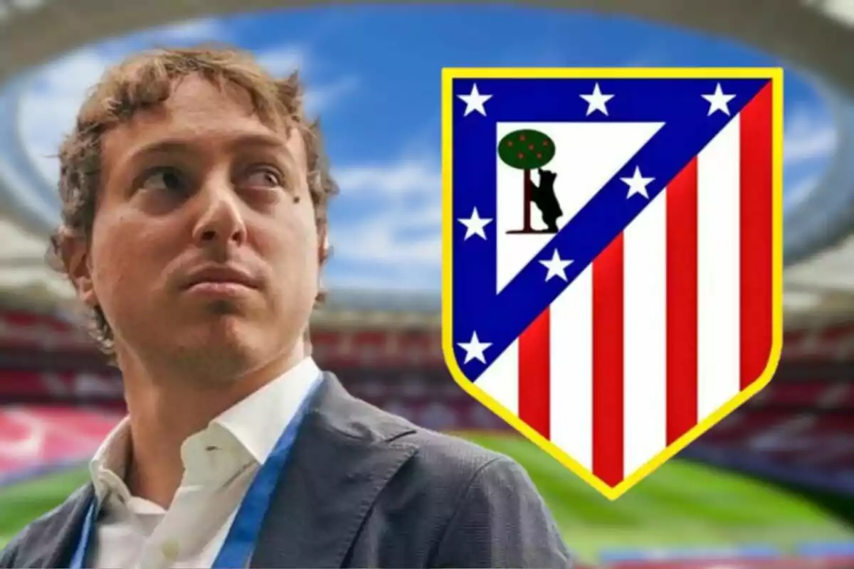 A man in a suit and tie is standing in front of a soccer stadium with the Atlético de Madrid crest beside him.