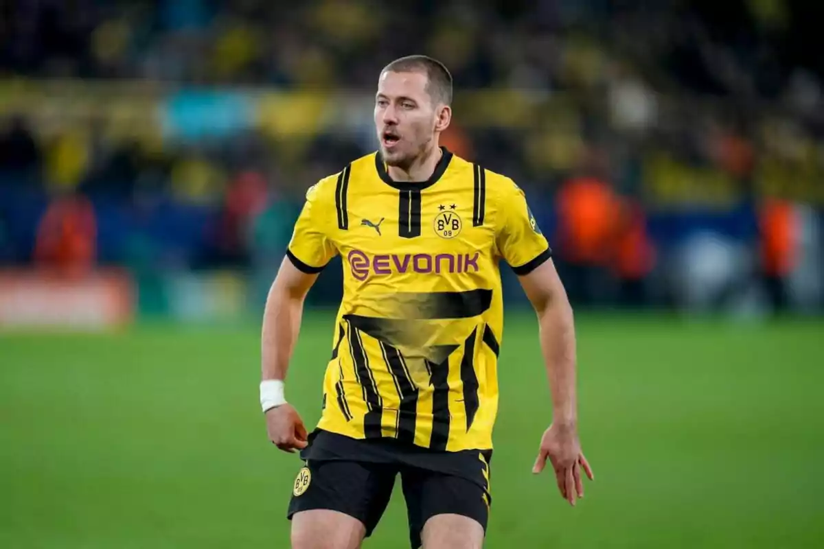 Jugador de fútbol con uniforme amarillo y negro del Borussia Dortmund en el campo de juego.