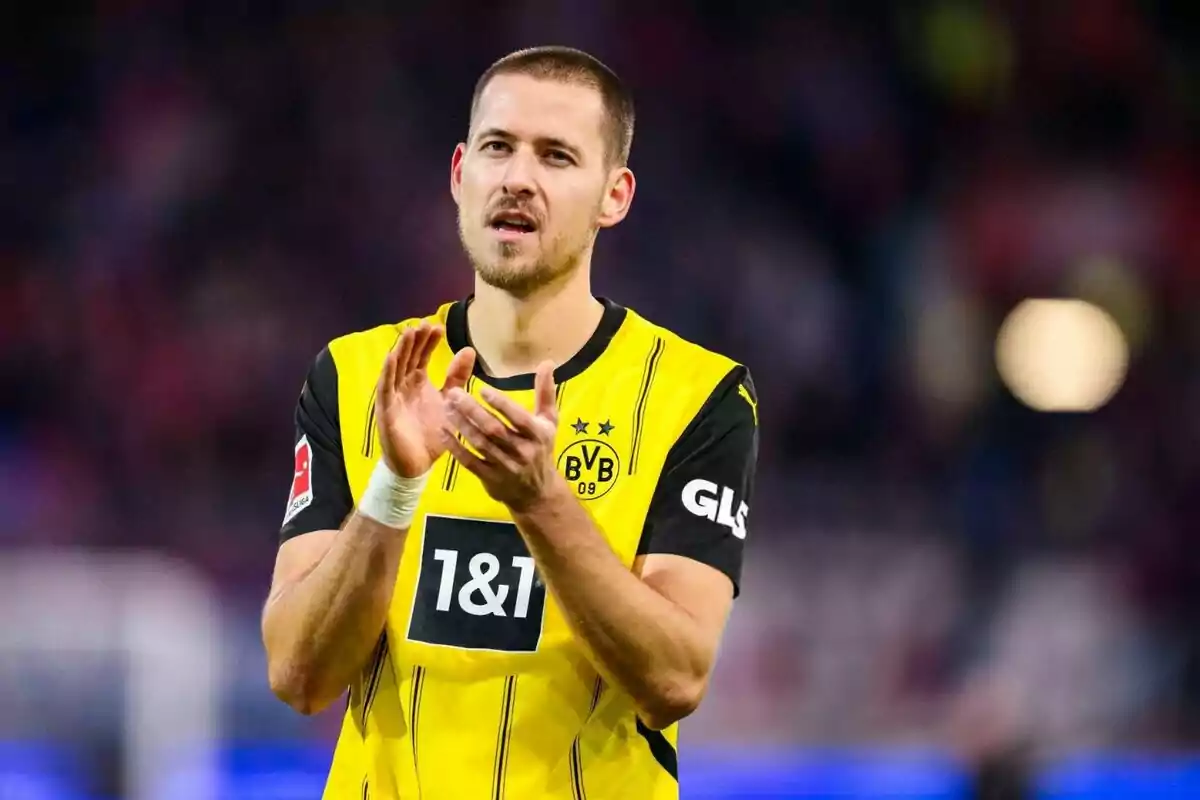 Un jugador de fútbol con uniforme amarillo y negro aplaude en el campo.