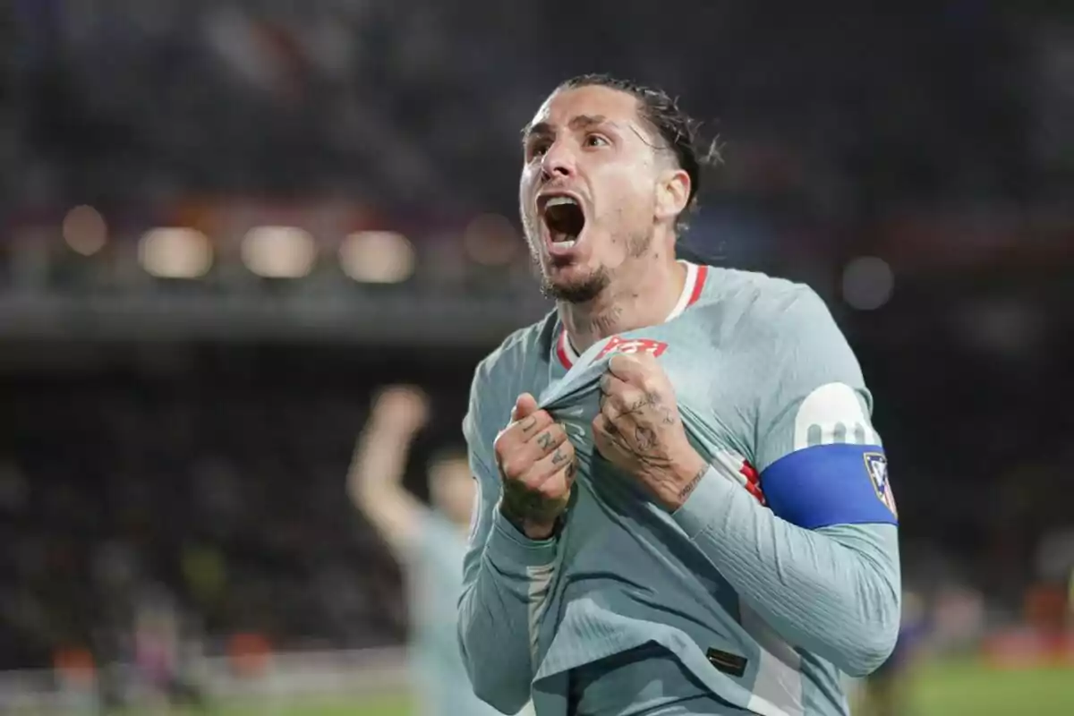 Un futbolista celebra efusivamente en el campo, mostrando emoción y energía mientras sostiene su camiseta.