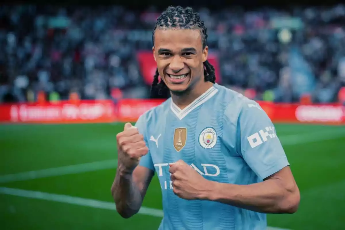 Un jugador de fútbol sonríe y celebra en el campo con el uniforme del Manchester City.