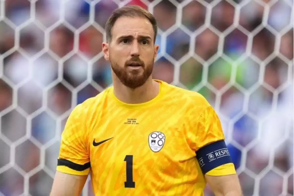 Portero de fútbol con uniforme amarillo y brazalete de capitán frente a una portería.