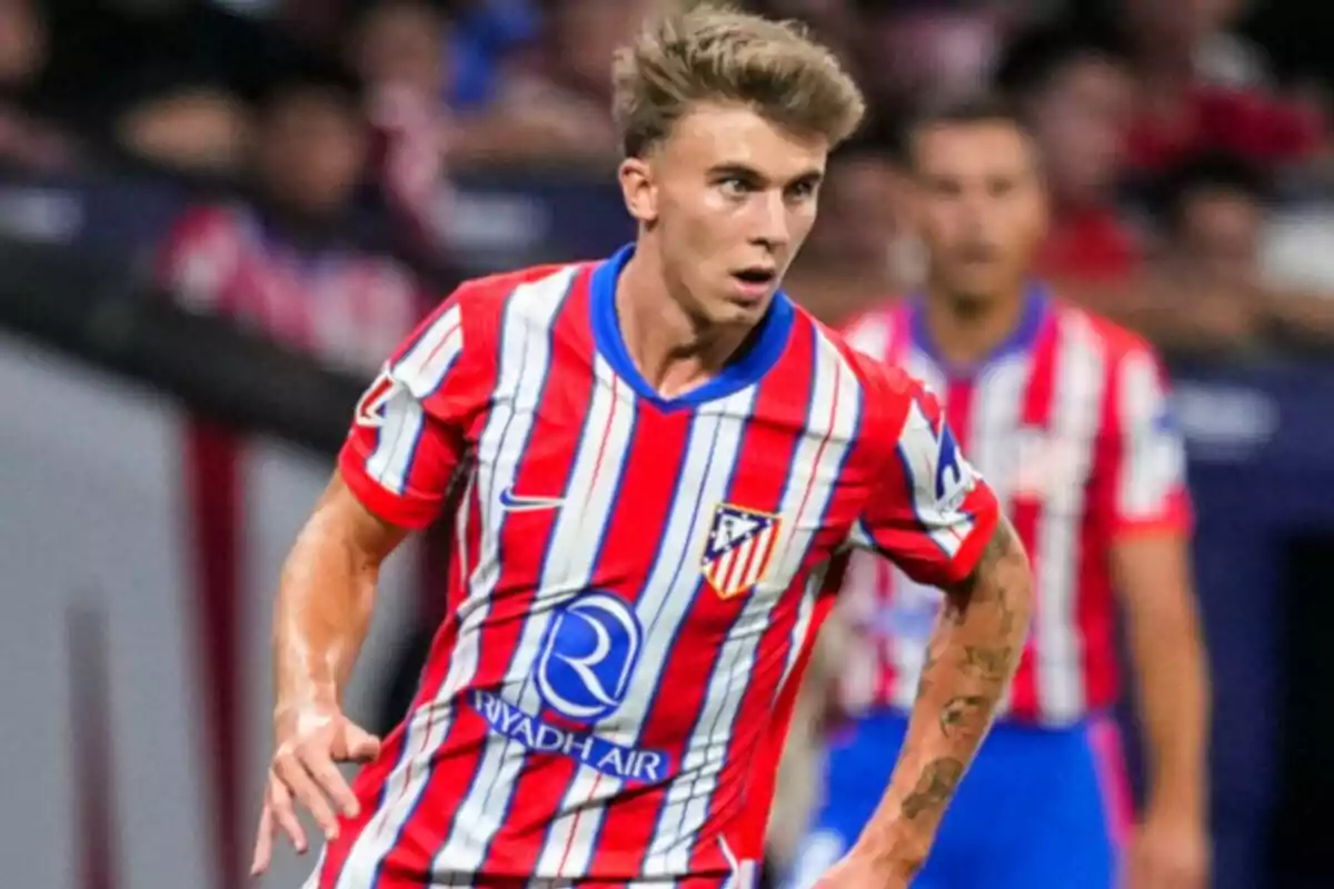 Jugador de fútbol con uniforme del Atlético de Madrid en el campo de juego.