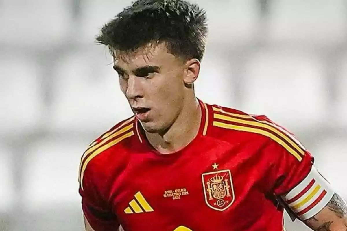 Jugador de fútbol con uniforme rojo de la selección española en el campo.