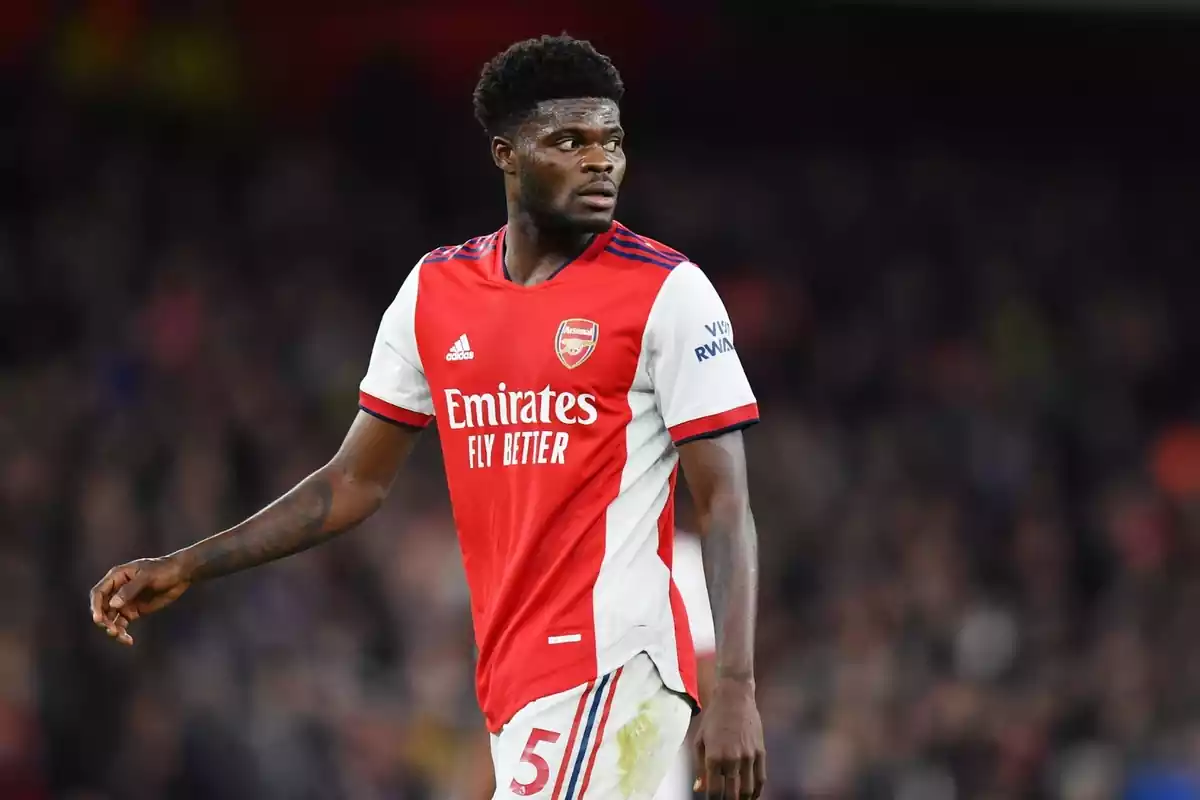 Thomas Partey mirando hacia atrás con la camiseta del Arsenal